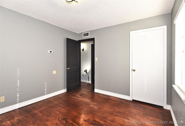 unfurnished bedroom featuring dark hardwood / wood-style flooring and a textured ceiling