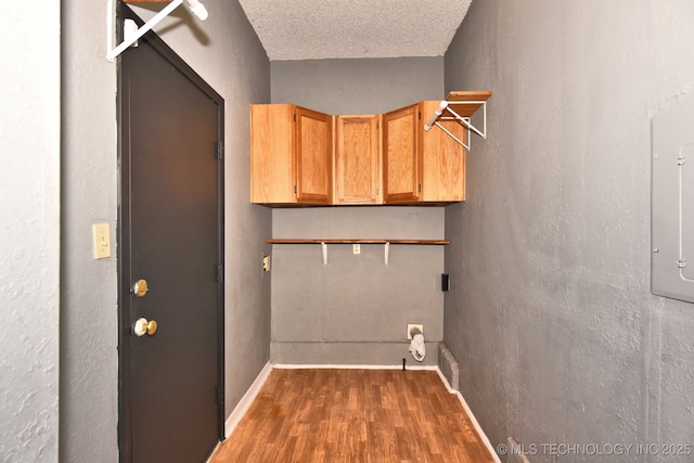 6273 E Marshall Pl, Tulsa, OK 74115 - washroom with wood finished floors, a textured ceiling, electric dryer hookup, cabinet space, and baseboards