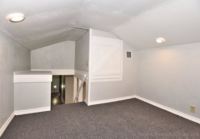 additional living space with lofted ceiling and dark colored carpet