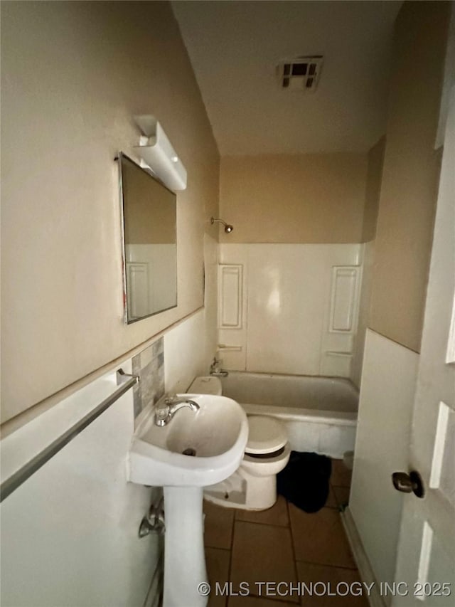 bathroom with tile patterned floors, toilet,  shower combination, and decorative backsplash