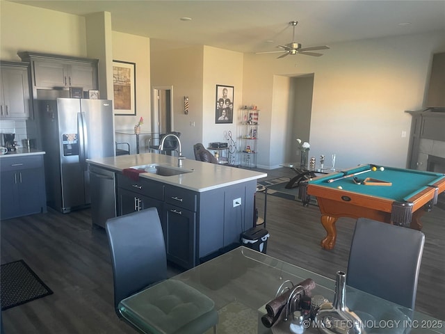 kitchen with sink, appliances with stainless steel finishes, dark hardwood / wood-style floors, a fireplace, and a center island with sink