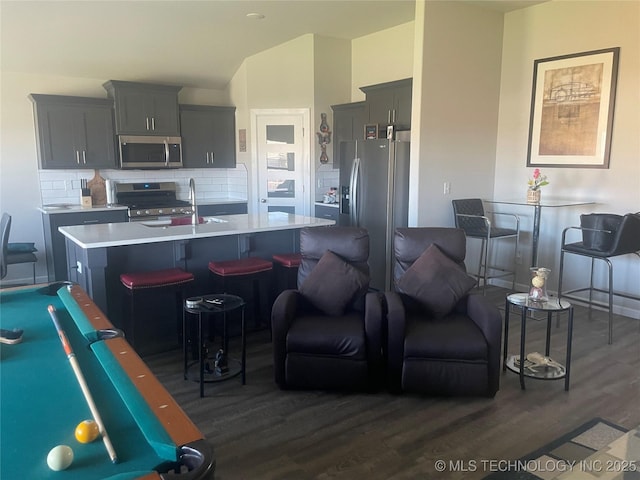 kitchen with a breakfast bar area, tasteful backsplash, dark hardwood / wood-style floors, gray cabinets, and stainless steel appliances