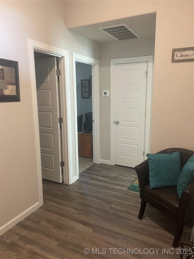 hallway featuring visible vents, dark wood-type flooring, and baseboards