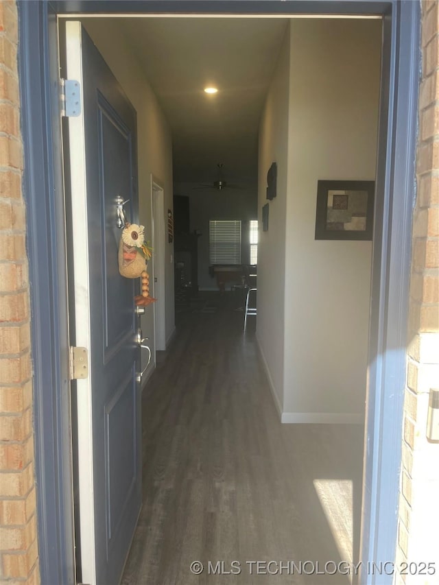 hallway featuring baseboards and wood finished floors