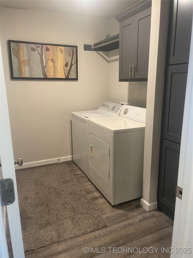 laundry area featuring dark wood-type flooring, cabinets, and washing machine and dryer