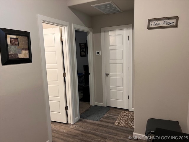 hallway featuring dark wood-style floors, visible vents, and baseboards