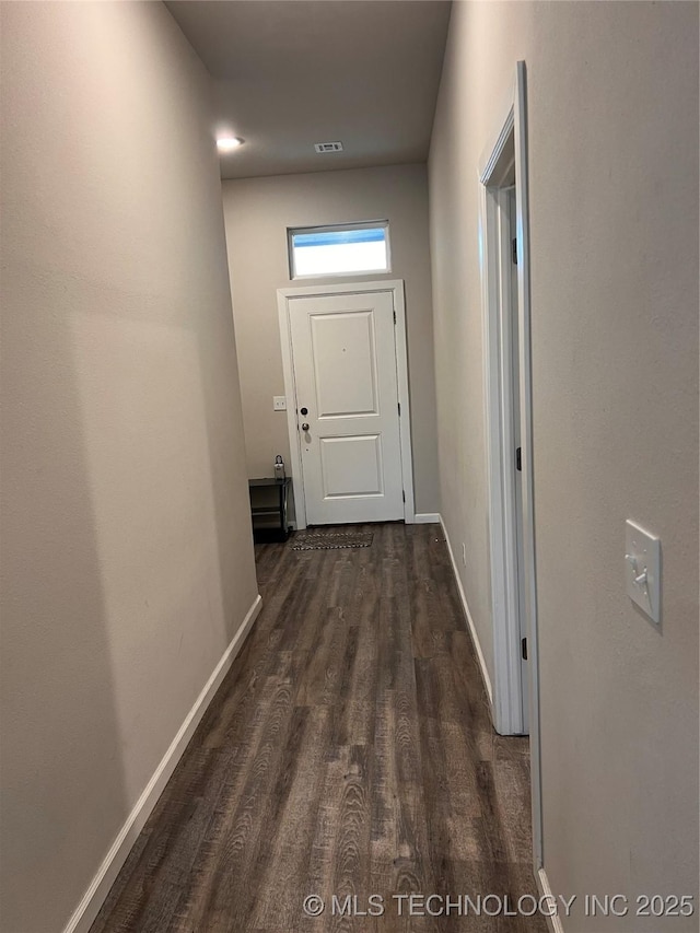 hall featuring dark wood finished floors, visible vents, and baseboards