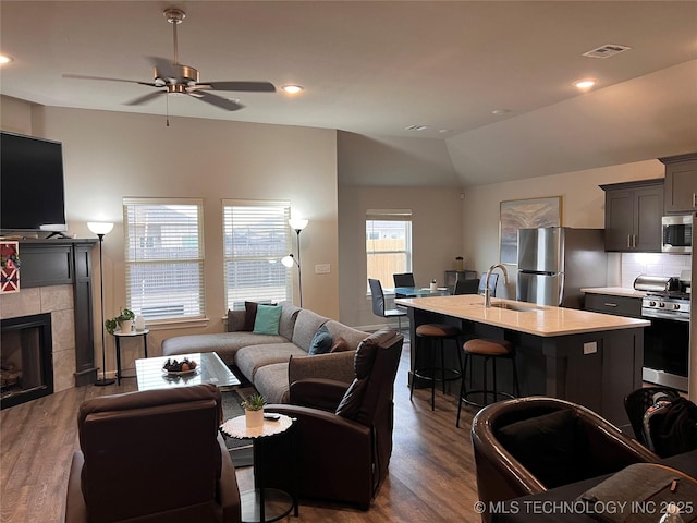 living room featuring dark wood finished floors, lofted ceiling, a fireplace, and visible vents