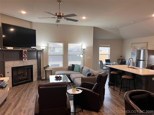 living room with vaulted ceiling, recessed lighting, a fireplace, and dark wood-style flooring