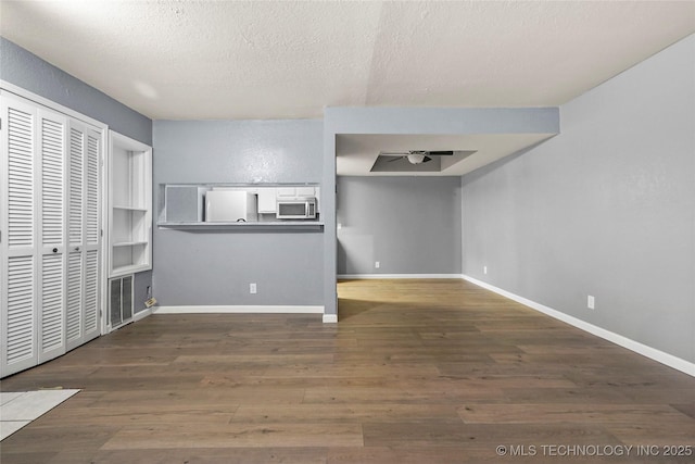 unfurnished living room with ceiling fan, dark hardwood / wood-style flooring, and a textured ceiling