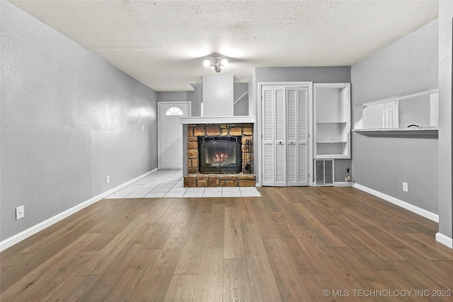 unfurnished living room featuring a fireplace, a textured ceiling, and light wood-type flooring