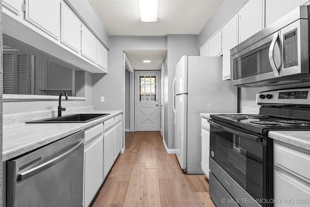 kitchen featuring white cabinetry, sink, light wood-type flooring, and appliances with stainless steel finishes