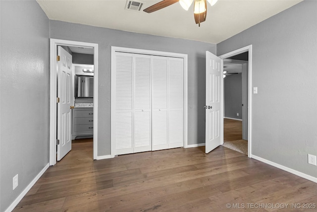 unfurnished bedroom with connected bathroom, a closet, dark hardwood / wood-style floors, and ceiling fan