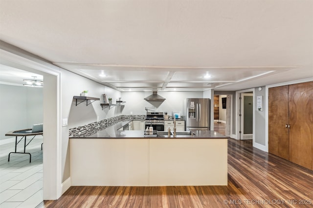 kitchen featuring sink, stainless steel appliances, dark hardwood / wood-style floors, kitchen peninsula, and wall chimney exhaust hood