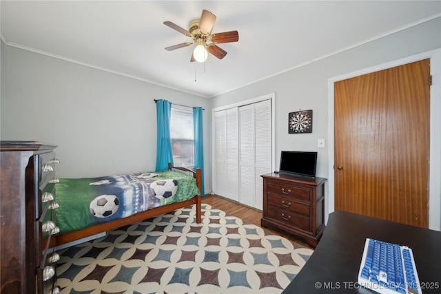 bedroom featuring crown molding, ceiling fan, light wood-type flooring, and a closet