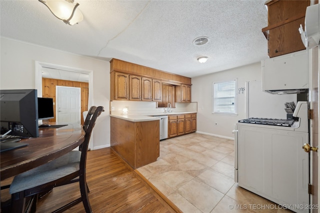 kitchen with sink, stainless steel dishwasher, kitchen peninsula, white gas stove, and a textured ceiling