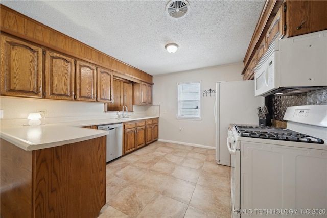 kitchen with white appliances, kitchen peninsula, sink, and a textured ceiling