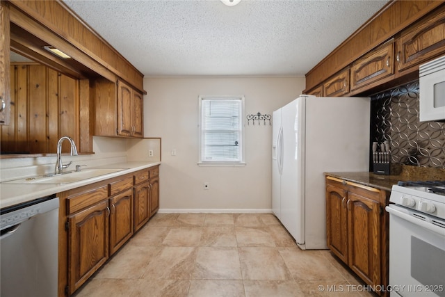 kitchen featuring white appliances, sink, a textured ceiling, and backsplash