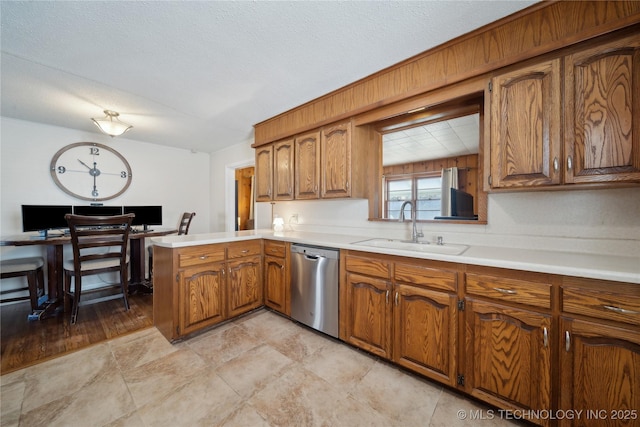 kitchen featuring stainless steel dishwasher, kitchen peninsula, sink, and a textured ceiling