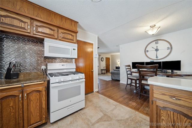 kitchen featuring a textured ceiling, white appliances, and decorative backsplash