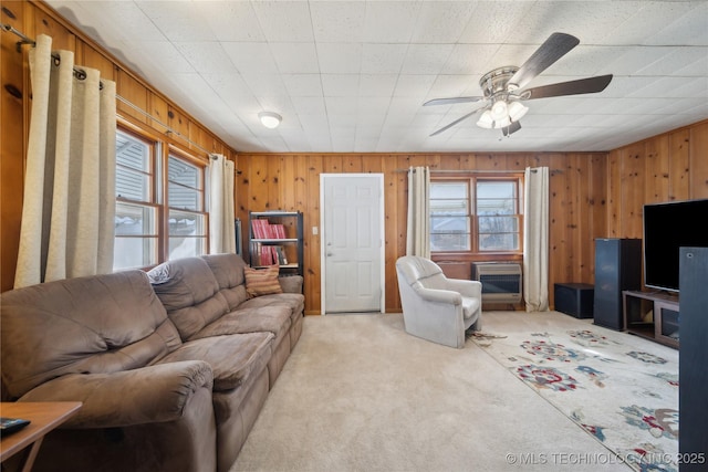 carpeted living room featuring ceiling fan and wood walls