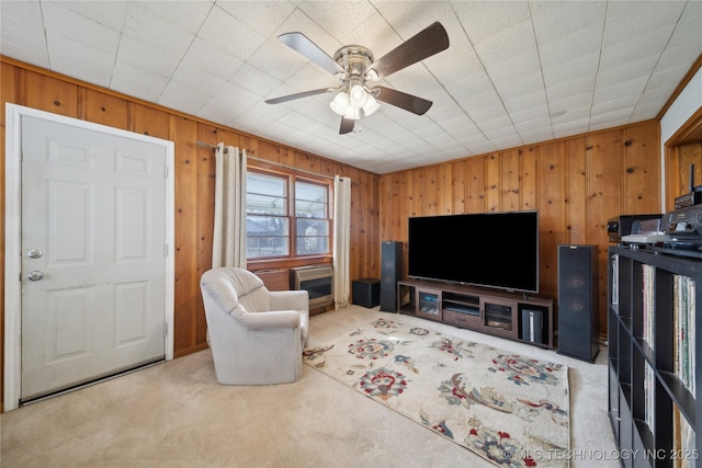 living room with ceiling fan, wooden walls, and carpet