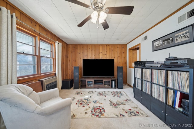 carpeted living room with a wall mounted air conditioner, ornamental molding, ceiling fan, and wood walls