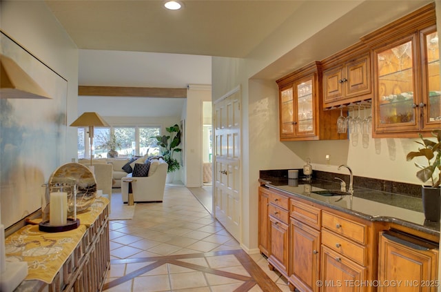 kitchen with sink, light tile patterned floors, and dark stone counters