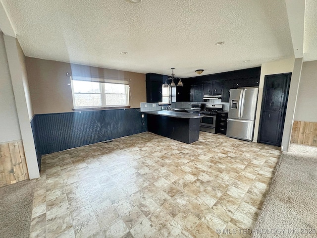 kitchen with wooden walls, a kitchen bar, hanging light fixtures, kitchen peninsula, and stainless steel appliances