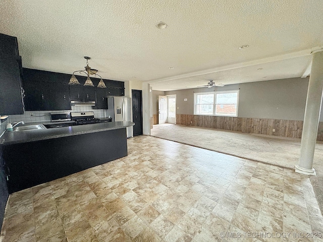 kitchen with sink, wooden walls, stainless steel appliances, and a textured ceiling