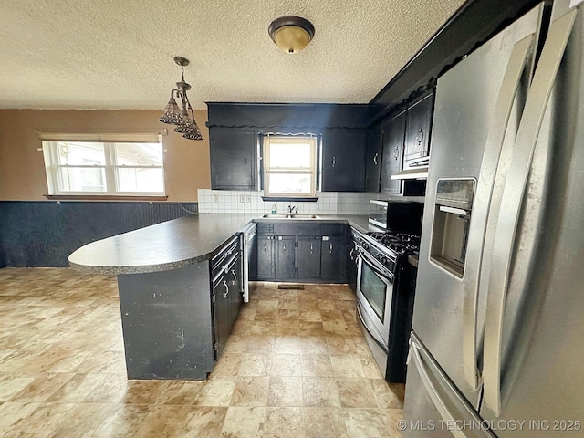 kitchen featuring sink, decorative light fixtures, kitchen peninsula, stainless steel appliances, and backsplash