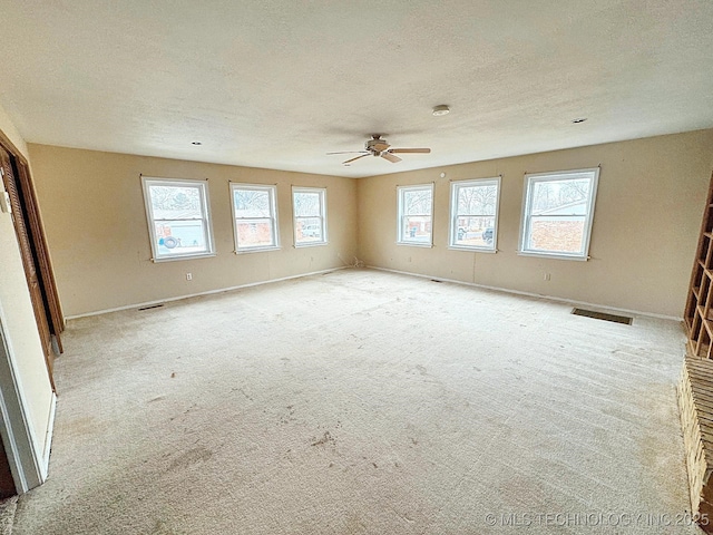 empty room featuring ceiling fan, light colored carpet, and a textured ceiling