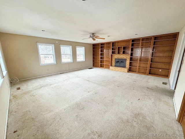 unfurnished living room with built in features, a fireplace, light colored carpet, and ceiling fan