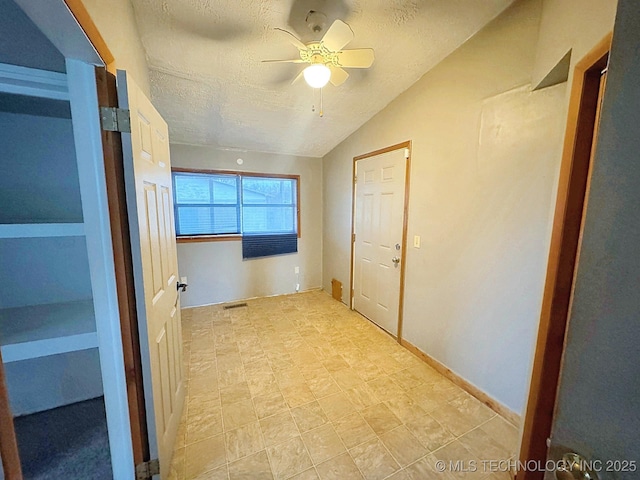 hall with vaulted ceiling and a textured ceiling