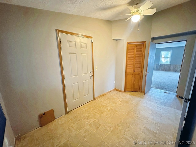 interior space featuring ceiling fan, a textured ceiling, and a closet