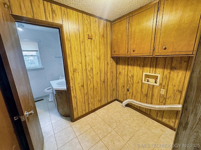 laundry room with wooden walls, cabinets, washer hookup, electric dryer hookup, and a textured ceiling