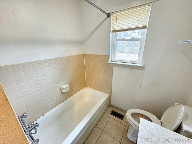 bathroom featuring a washtub, tile patterned floors, and toilet