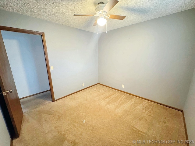 spare room featuring ceiling fan, light colored carpet, and a textured ceiling