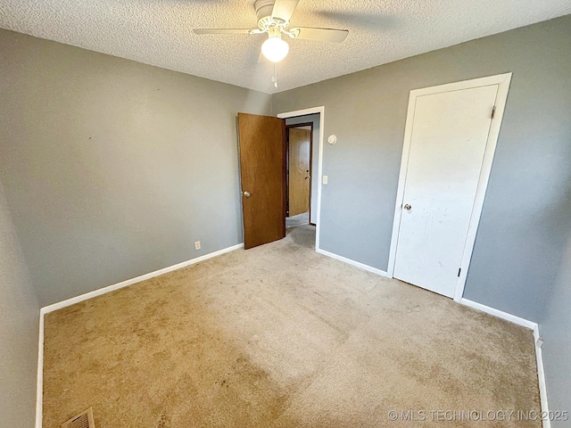 unfurnished bedroom featuring ceiling fan, light carpet, and a textured ceiling