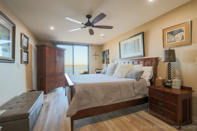 bedroom featuring access to exterior, a water view, ceiling fan, and wood-type flooring