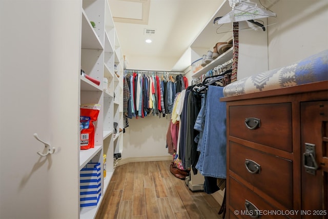 walk in closet with light hardwood / wood-style flooring