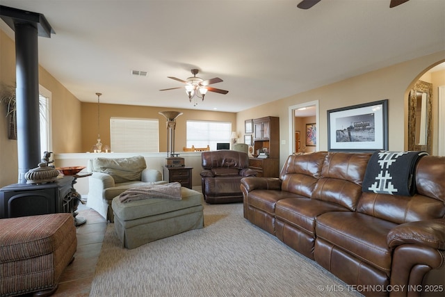 living room with a wood stove and ceiling fan