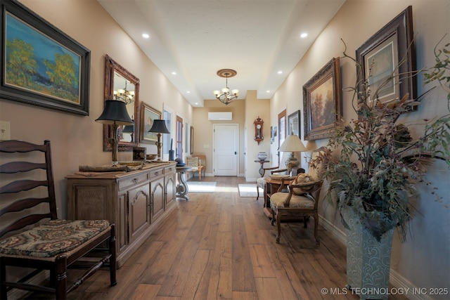 hall featuring an AC wall unit, a notable chandelier, and wood-type flooring