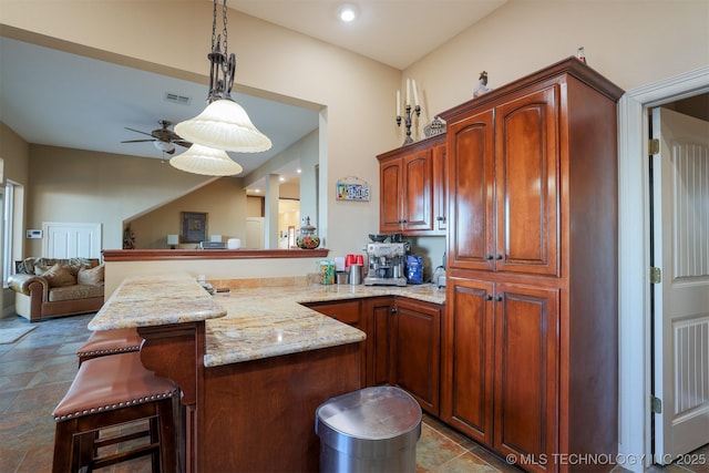 kitchen with light stone counters, a kitchen breakfast bar, ceiling fan, kitchen peninsula, and hanging light fixtures