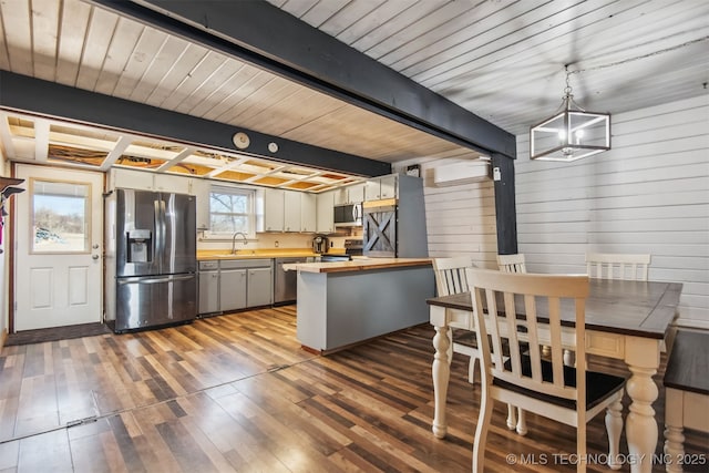 kitchen featuring butcher block counters, sink, hardwood / wood-style flooring, pendant lighting, and stainless steel appliances