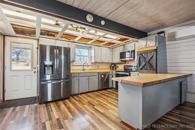 kitchen featuring sink, a wall mounted air conditioner, stainless steel appliances, and hardwood / wood-style floors