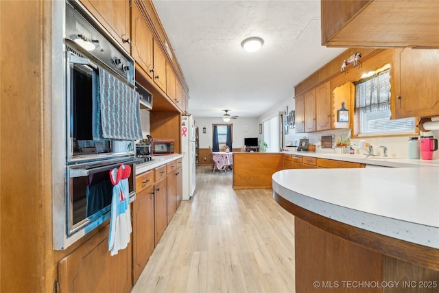 kitchen featuring tasteful backsplash, white refrigerator, light hardwood / wood-style floors, kitchen peninsula, and stainless steel double oven