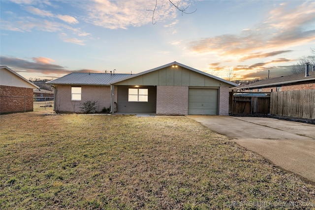 view of front facade featuring a garage, brick siding, fence, driveway, and a yard