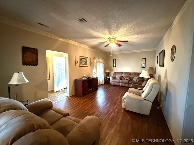 living room with ceiling fan, dark wood-type flooring, ornamental molding, and a textured ceiling