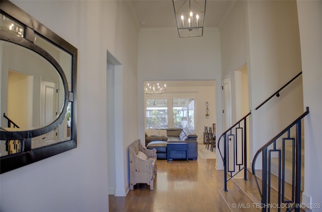 entryway with hardwood / wood-style floors, crown molding, a chandelier, and a high ceiling